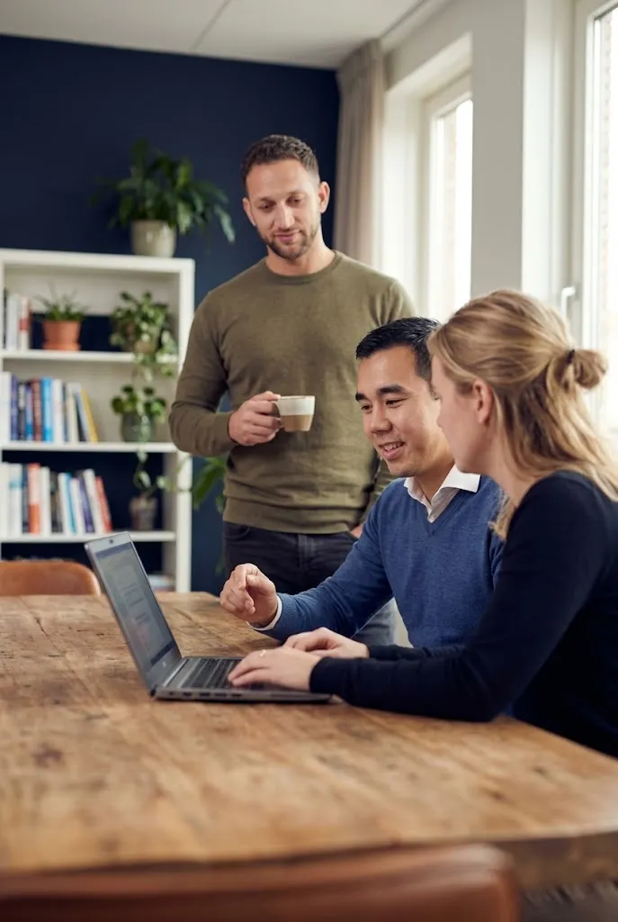 Drie YourFlow teamleden bekijken tevreden het werkende eindresultaat op een laptop